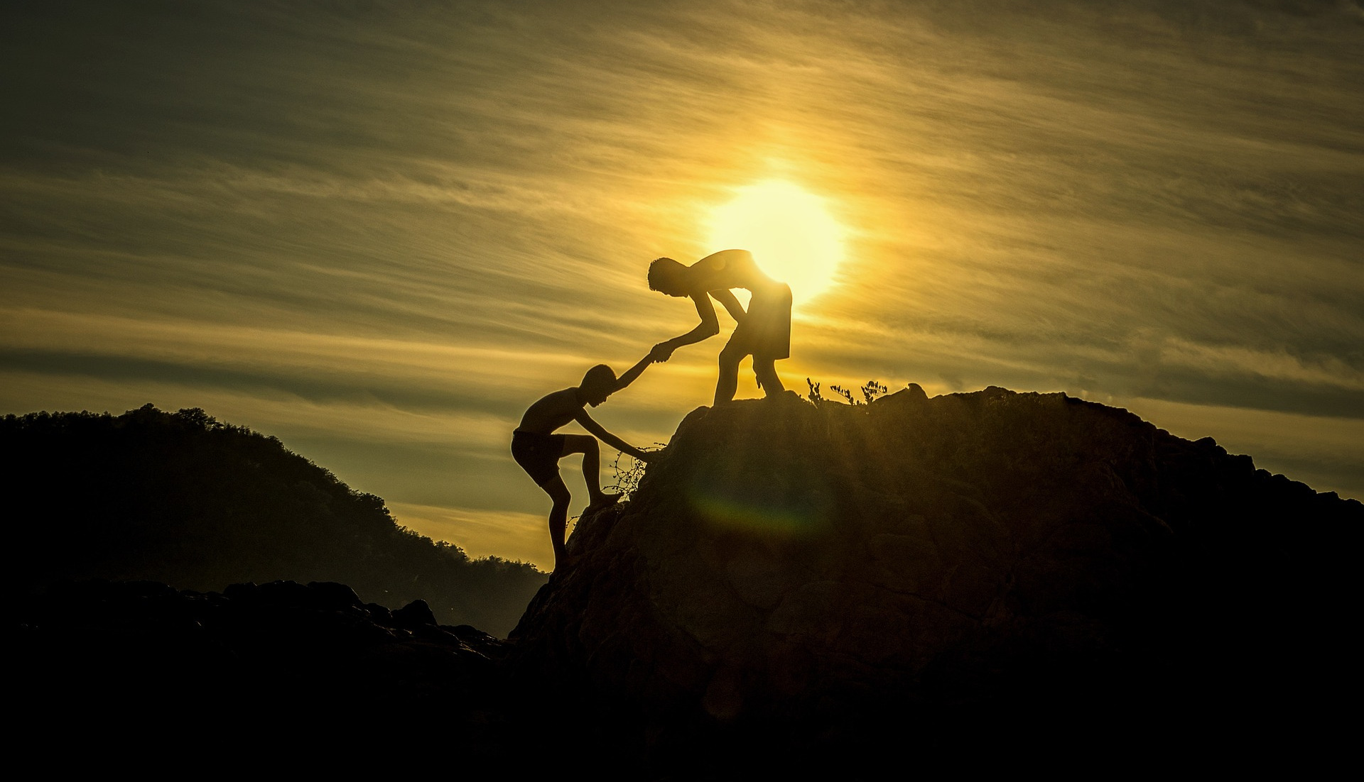 Bild eines Menschen, der einen anderen auf einen Berg hilft als Symbolbild für die Betreuung